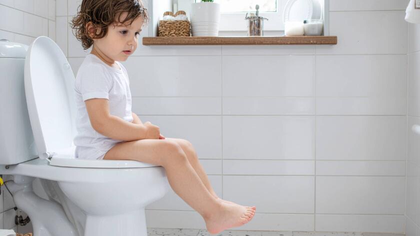 Μικρό παιδί κάθεται στη λεκάνη του μπάνιου προσπαθώντας να χρησιμοποιήσει την τουαλέτα μόνο του