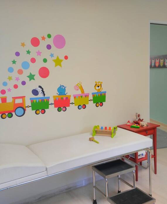 Παιδικό εξεταστήριο με διακοσμητικό αυτοκόλλητο τοίχου τρενάκι, παιδικά παιχνίδια και αναπαυτικό εξεταστικό κρεβάτι